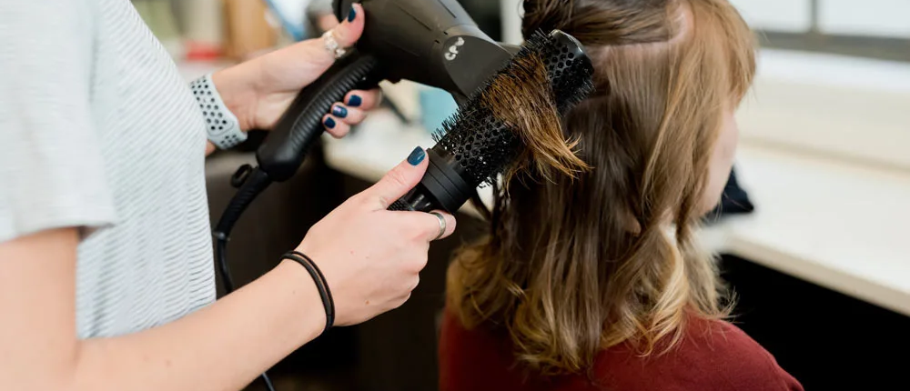 Junge Frau wird mit Föhn und Bürste gestylt - Der beste Friseur