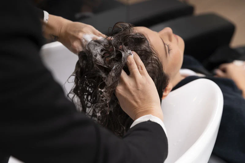 Frau erhält Haarwäsche im Friseursalon - Hair Profili By Luigi