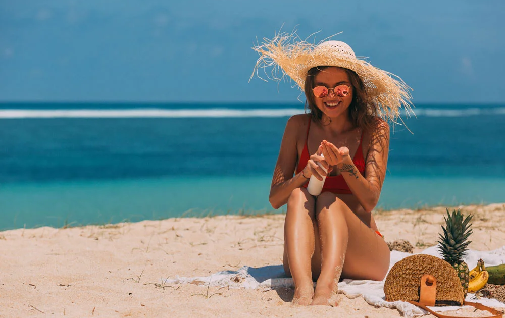 Haarpflege nach dem Strandurlaub - junge Frau mit Strohhut am Strand.